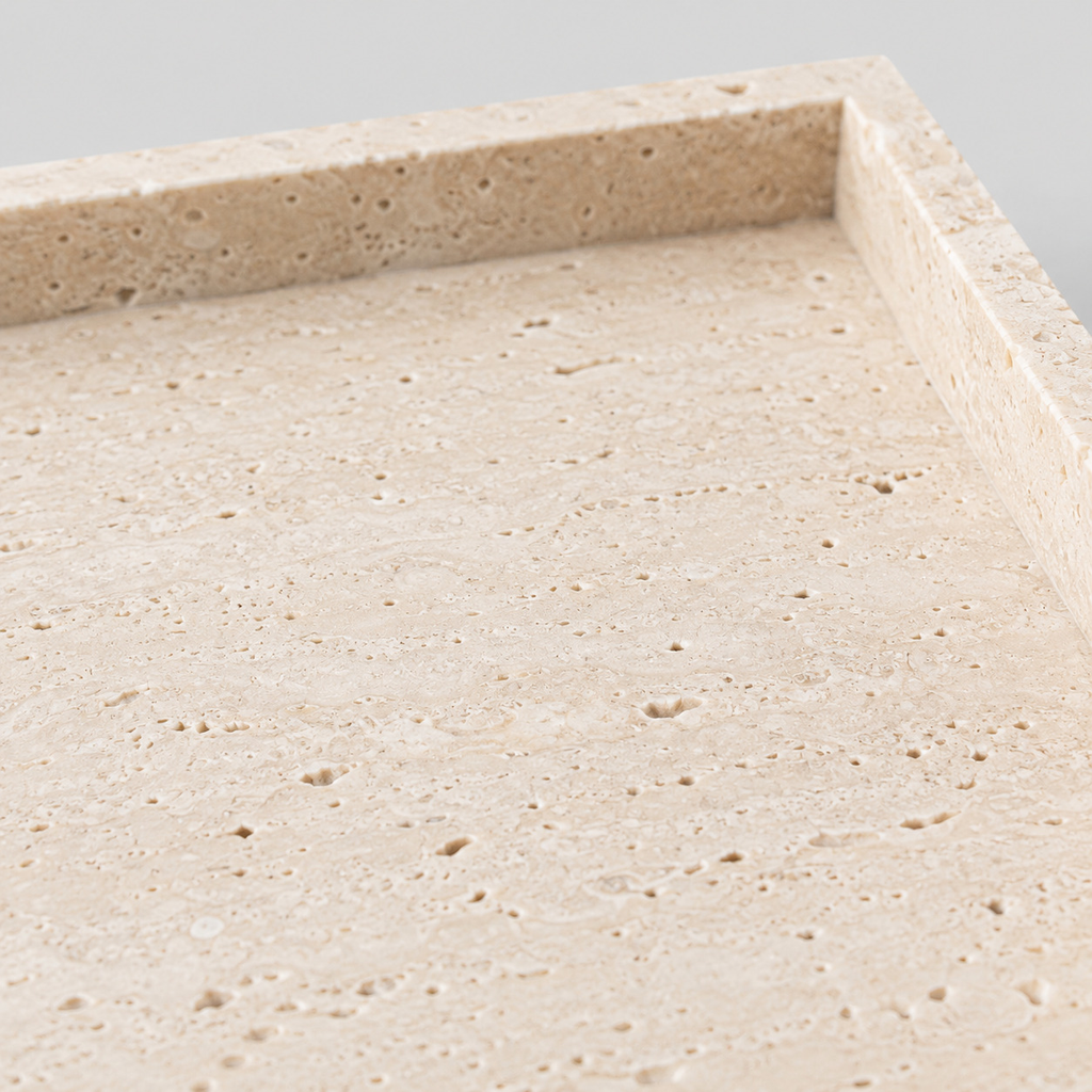 Close up of the porous pitted surface texture of the natural beige travertine rectangular tray.