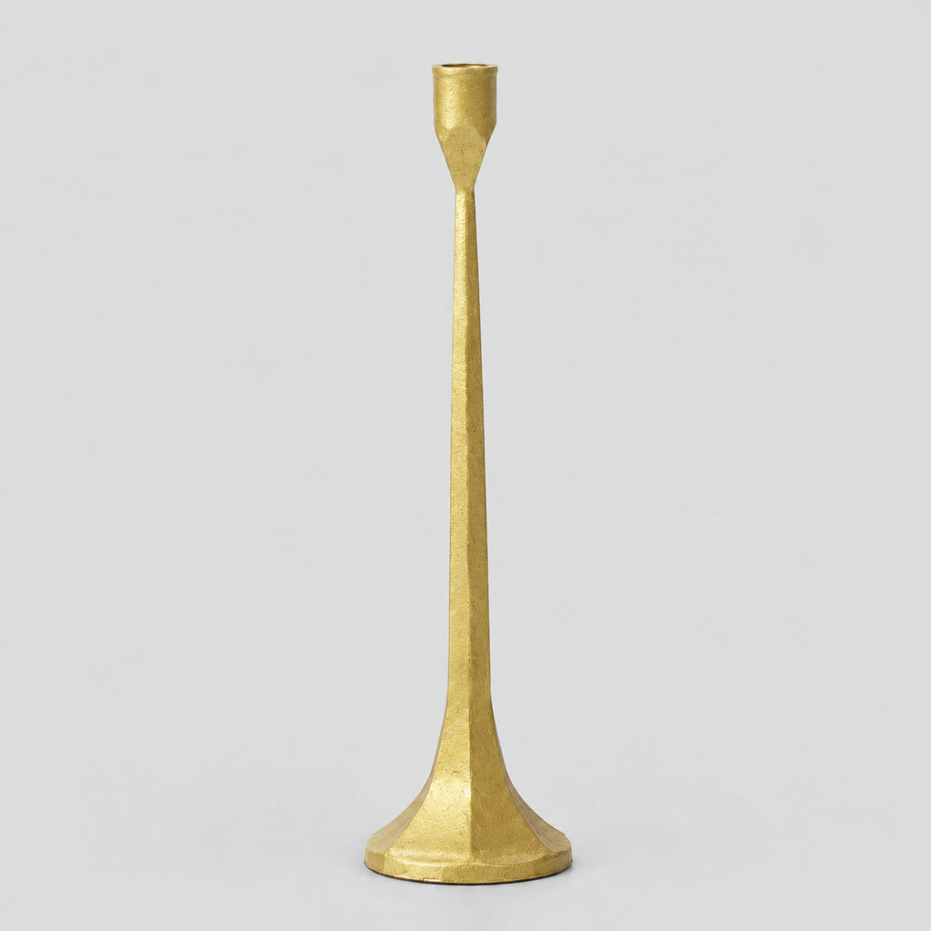 Cast iron taper candle holder in Brass on a light gray studio background.