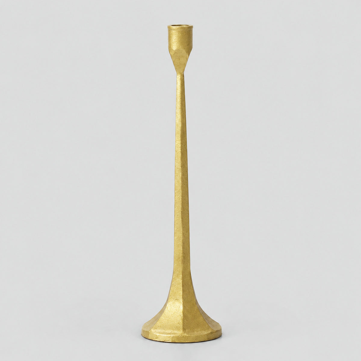 Cast iron taper candle holder in Brass on a light gray studio background.