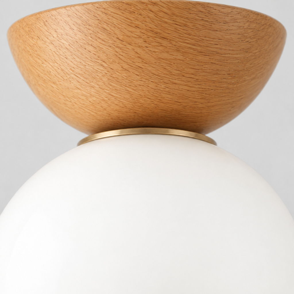 Close up of the rim where the glass shade meets the brass fitter on the natural wood flush mount light.