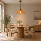 Wavy rattan pendant light lit hanging above a 90 cm round oak dining table.