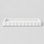 White rectangular fluted travertine vanity tray on a light neutral gray studio background.