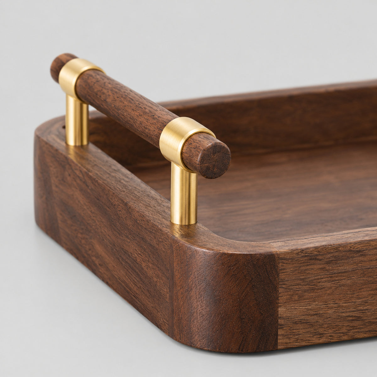 Close up of the brass bracket supporting the wooden bar handle of the walnut serving tray.