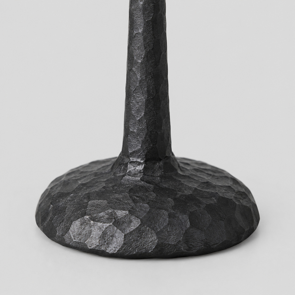 Close up of the hammered round base of the matte black cast-iron taper candle holder.