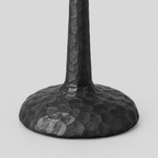 Close up of the hammered round base of the matte black cast-iron taper candle holder.