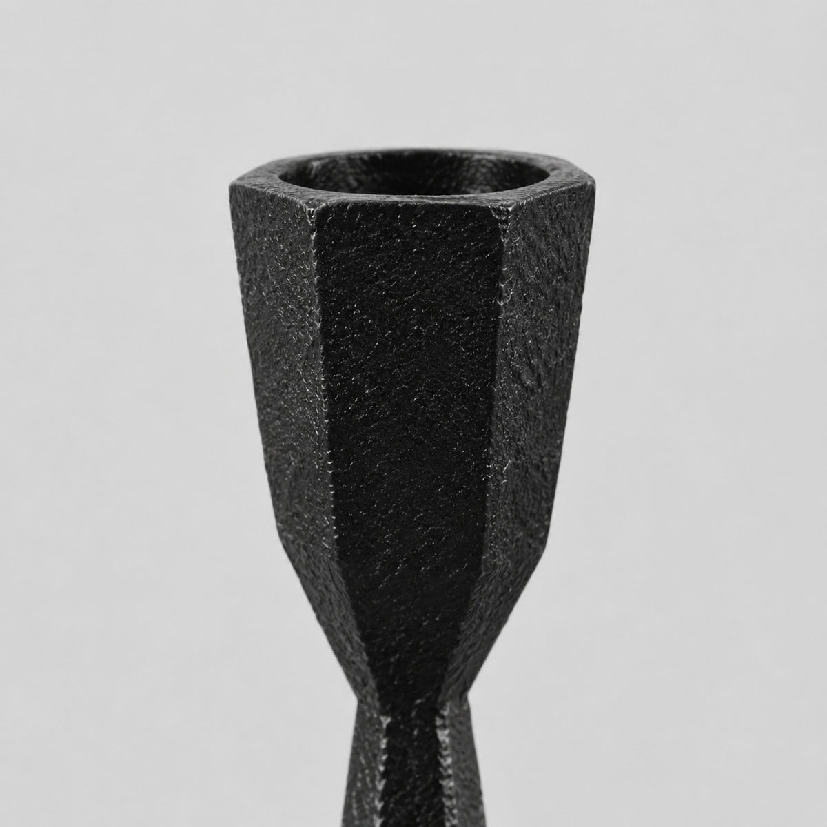 Close up of the faceted rim of the candle cup of the set of two faceted cast iron taper candle holders