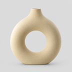 Hollow round ceramic vase in beige on a light neutral gray studio background.