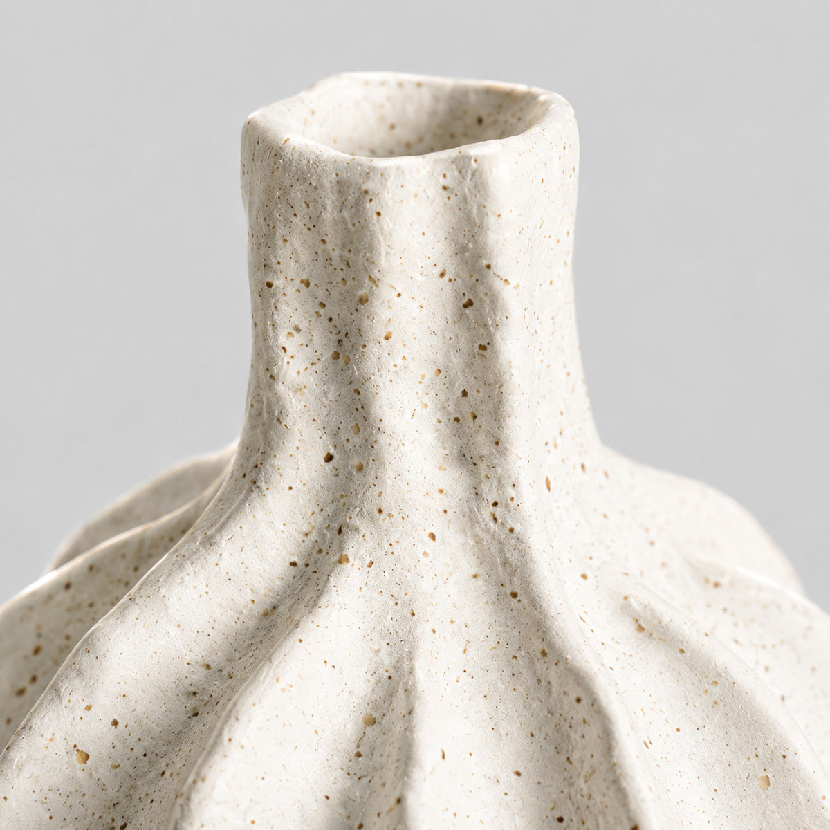 Close up of the speckled matte glaze along the fluted ridges of the coarse ceramic vase in Speckled White.
