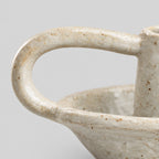 Close up of the curved loop handle of the Speckled Off-White ceramic taper candle holder