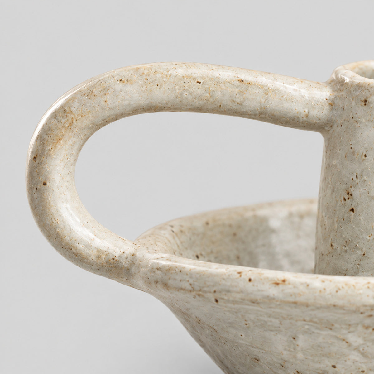 Close up of the curved loop handle of the Speckled Off-White ceramic taper candle holder