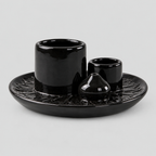 Black ceramic incense and candle tray on a light gray studio background