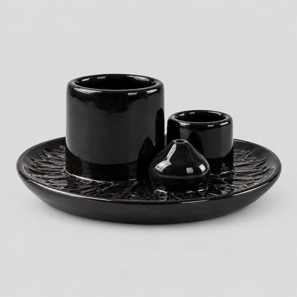 Black ceramic incense and candle tray on a light gray studio background
