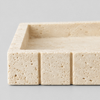 Close up of the porous honed stone surface texture of the beige travertine vanity tray.