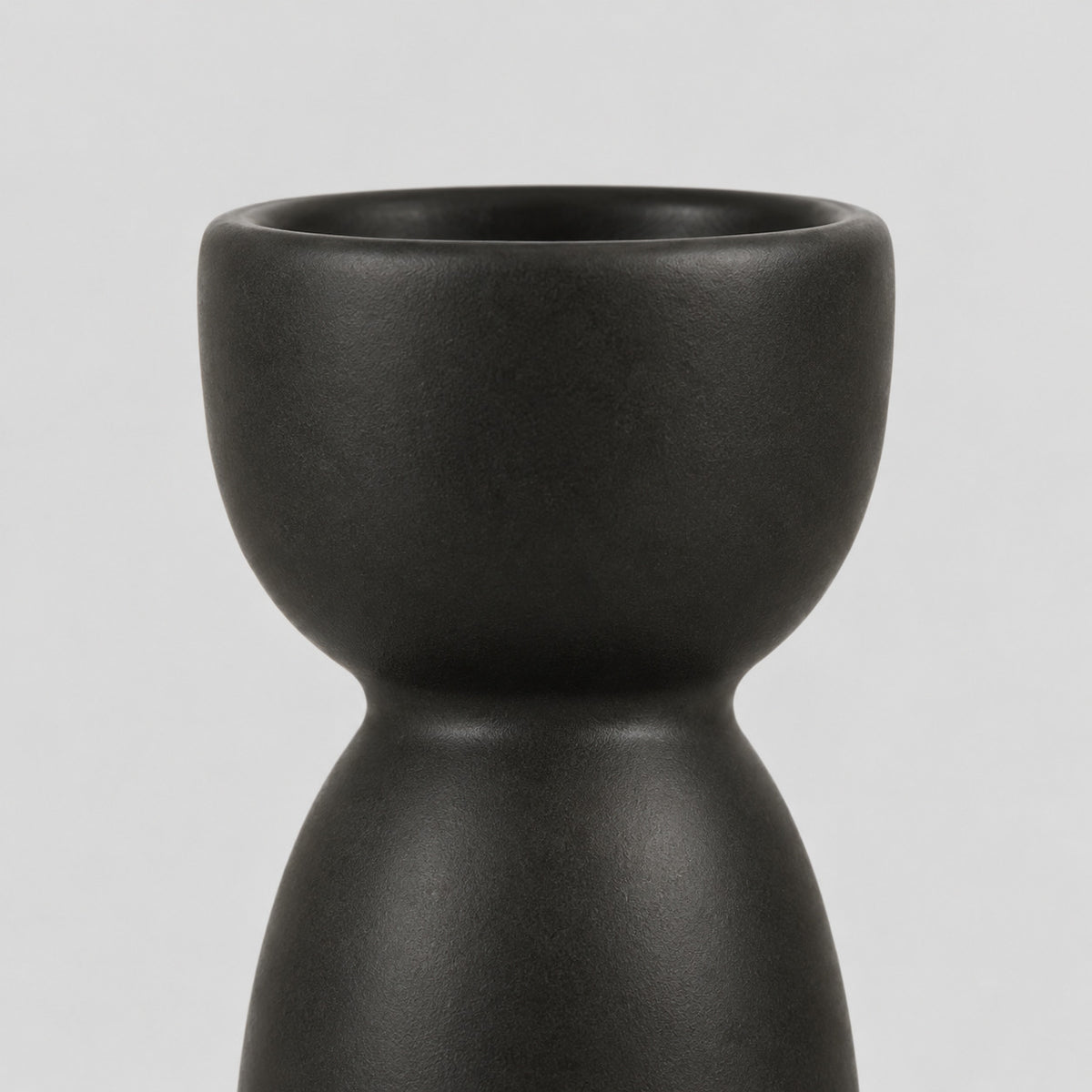 Close up of the smooth rounded cup rim of the matte ceramic taper candle holder.