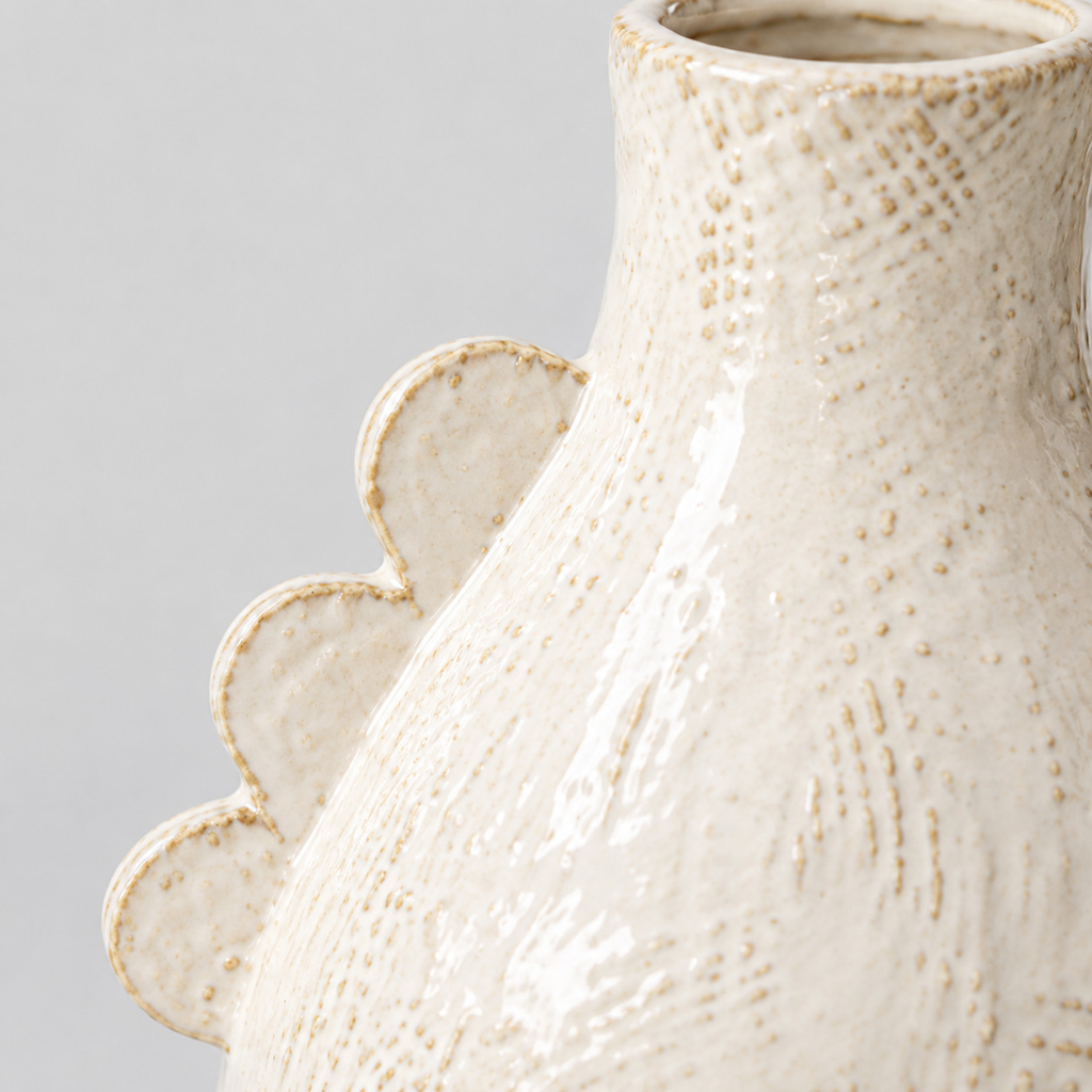 Close up of the decorative scalloped ridge along the shoulder of the off-white scalloped ceramic vase
