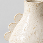 Close up of the decorative scalloped ridge along the shoulder of the off-white scalloped ceramic vase