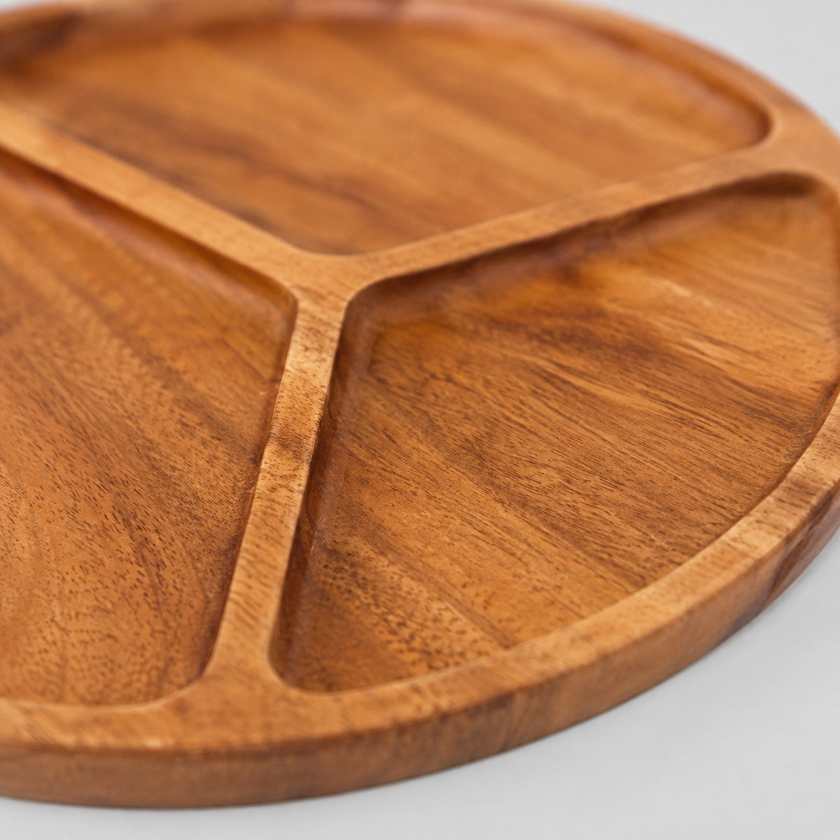 Close up of the natural wood grain surface texture of the three-compartment round wooden serving tray