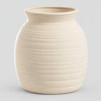 Off-white horizontally ribbed ceramic jar vase on a light gray studio background.