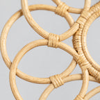 Close up of the wrapped cane joints connecting the outer loops of the decorative looped rattan wall frame in Natural Rattan.