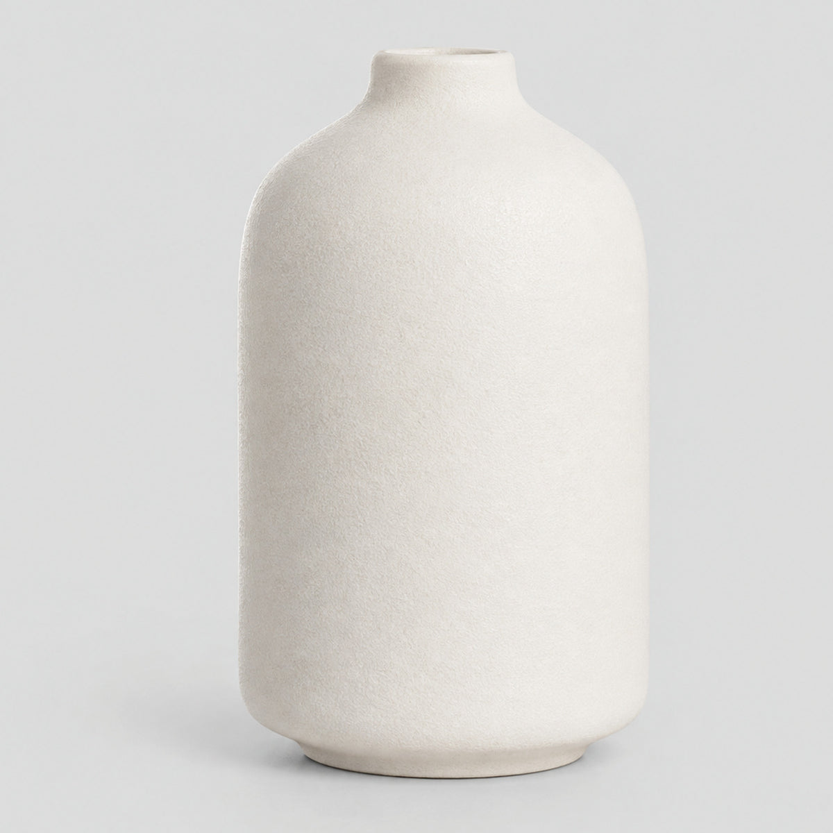 Off-White matte ceramic bud vase standing alone on a light neutral gray studio background.
