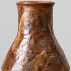 Close up of the textured rustic glaze across the tapered body of the coarse pottery bud vase.