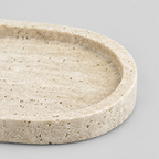 Close up of the shallow carved rim of the oval stone vanity tray in Beige Travertine