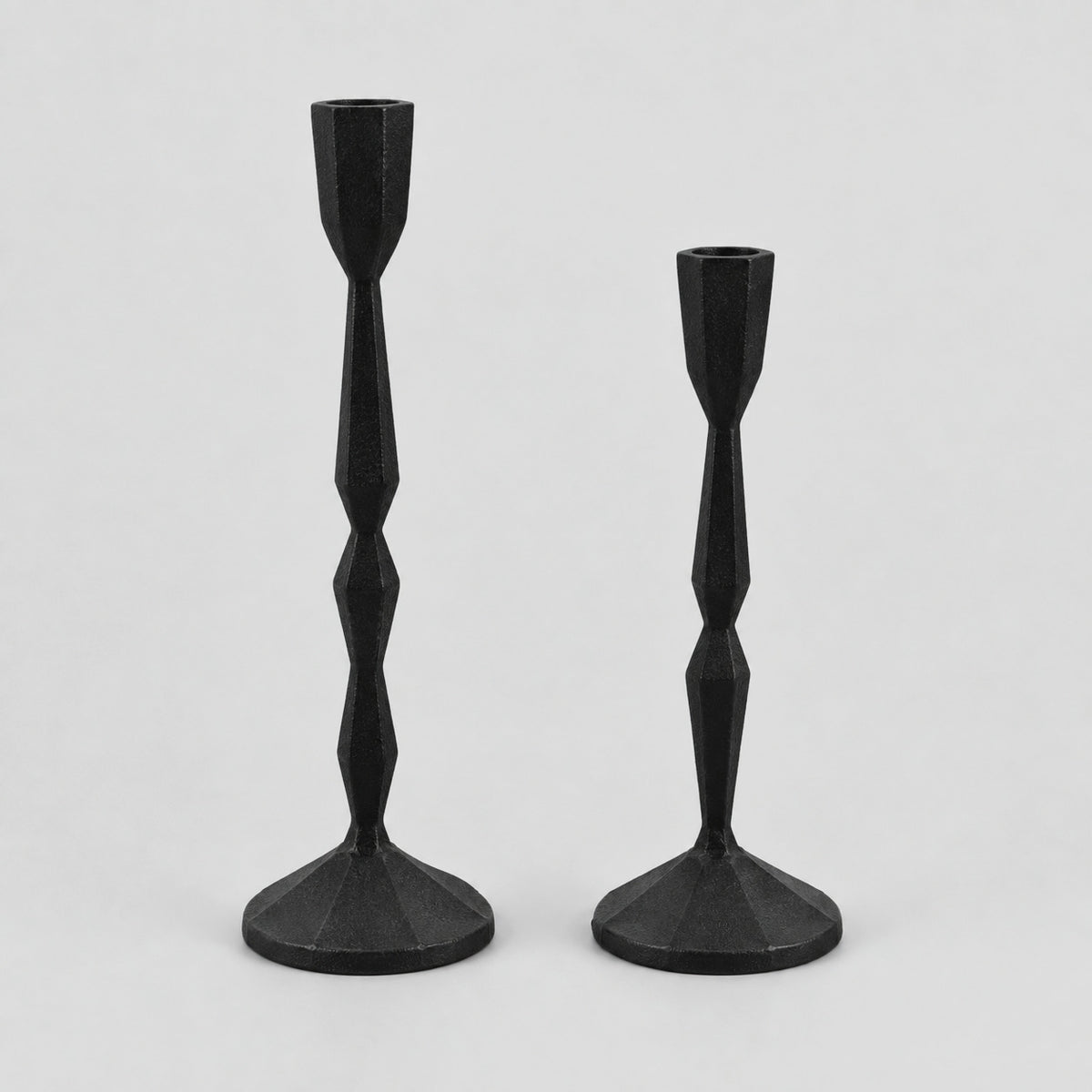 Set of two faceted cast iron taper candle holders in Matte Black on a light gray studio background