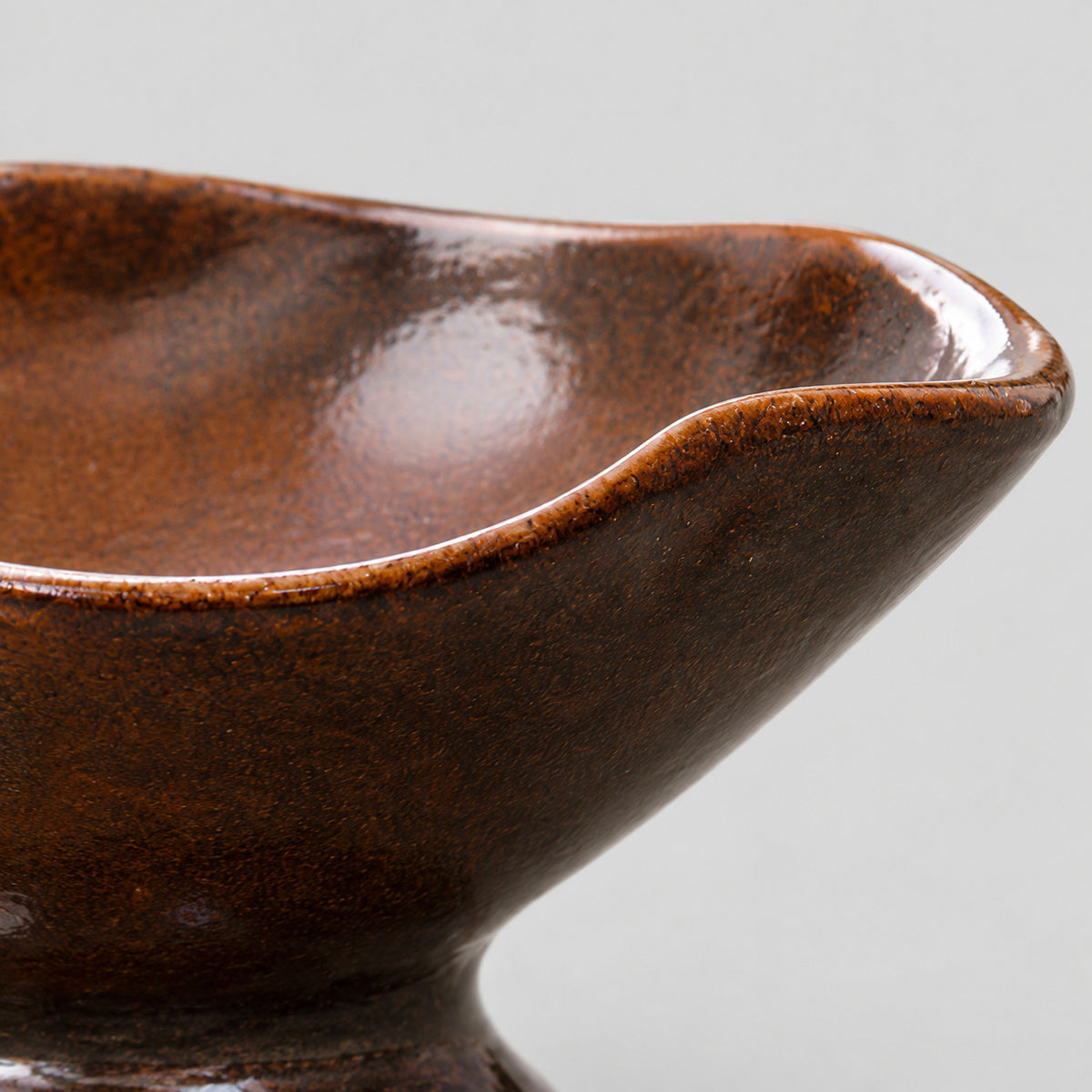 Close up of the undulating rim of the ceramic footed planter bowl in Glazed Brown.