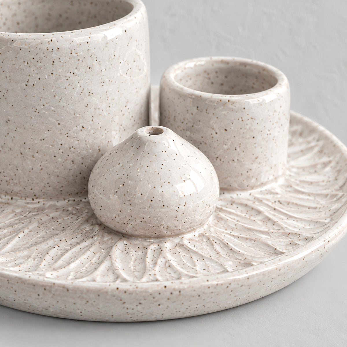 Close up of the embossed petal pattern on the tray of the Speckled White ceramic incense dish