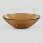 Shallow glass bowl with black rim in Amber on a light gray studio background.