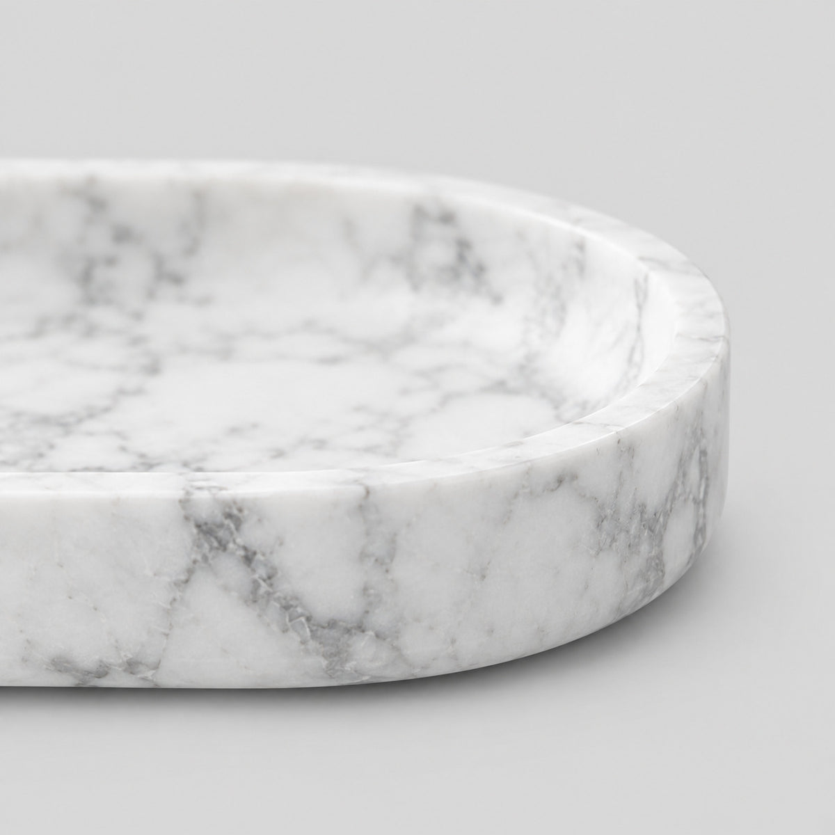 Close up of the smooth rounded rim of the oval stone catchall tray in Carrara White.