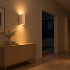 Travertine block wall sconce lit in the evening mounted on the plaster wall of a hallway beside an 80 cm wide doorway, the only light in the room