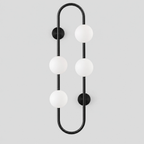 Matte Black pill-frame frosted globe wall sconce on a light gray studio background.