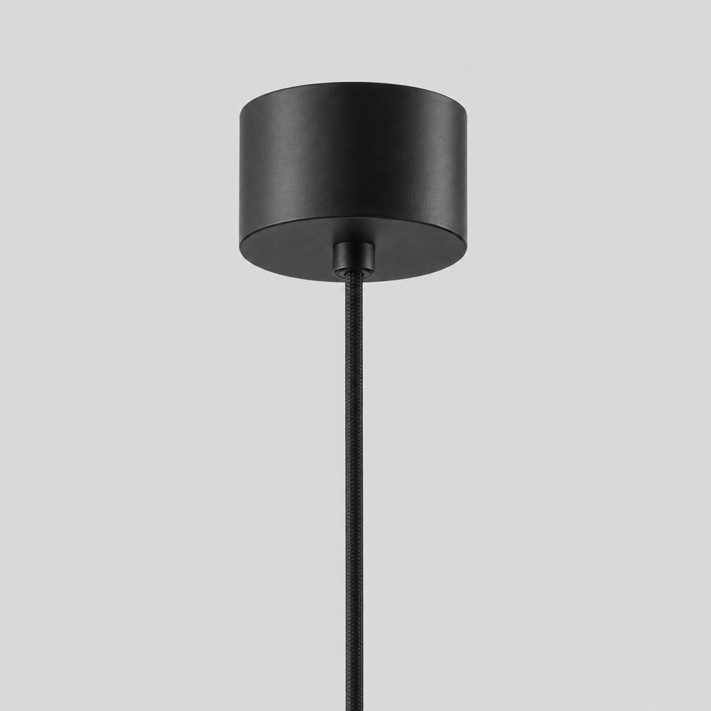 Close up of the round canopy against the wall of the Matte Black slender teardrop pendant light.