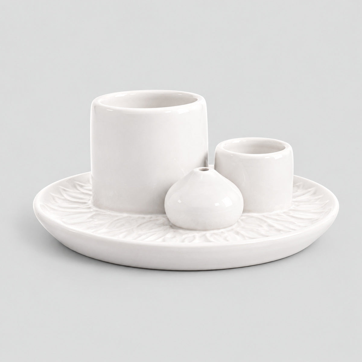 White ceramic incense dish on a light gray studio background