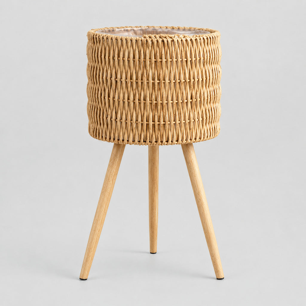Standing woven rattan planter basket on wooden tripod legs in Natural Rattan on a light gray studio background.
