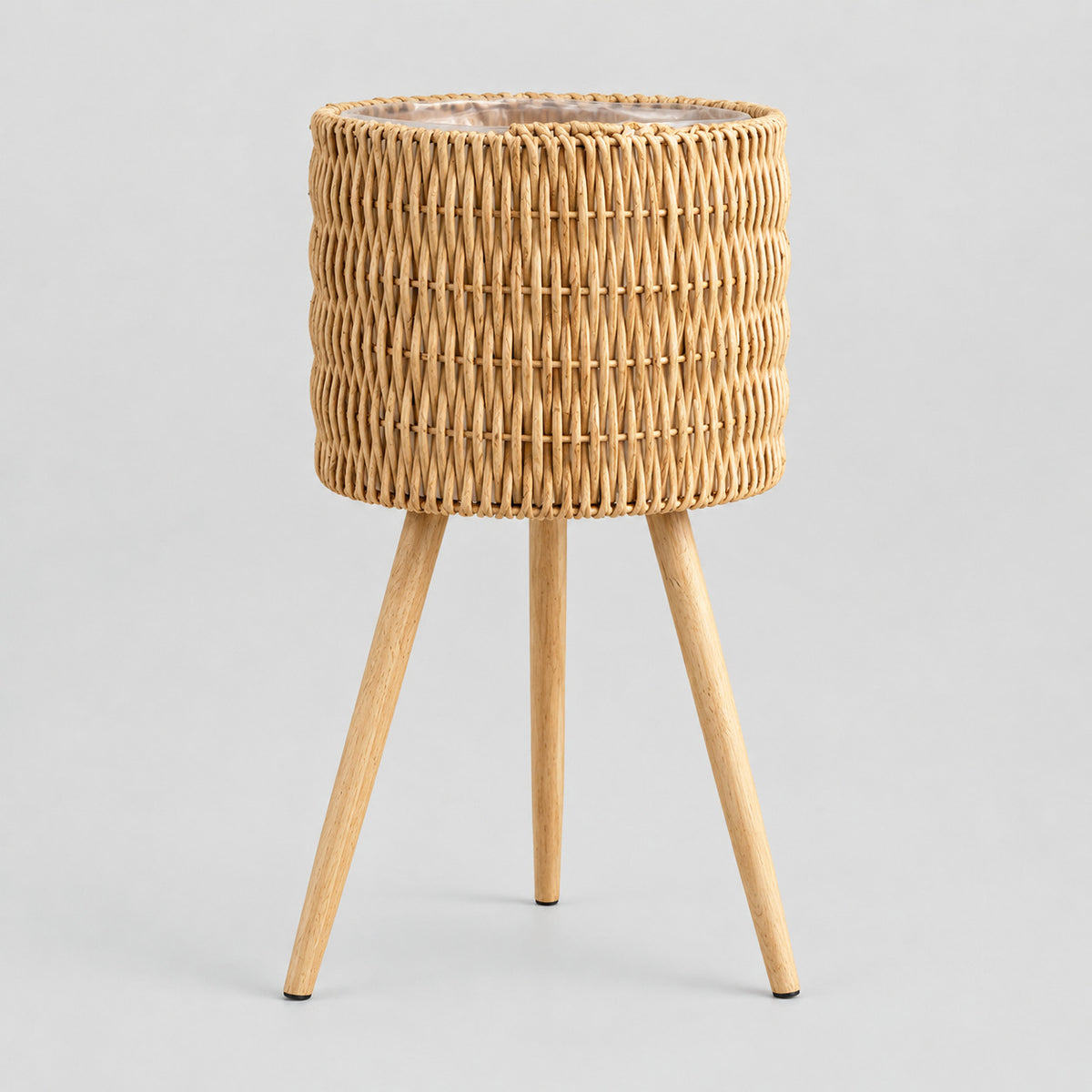 Standing woven rattan planter basket on wooden tripod legs in Natural Rattan on a light gray studio background.