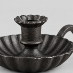 Close up of the fluted rim of the drip pan of the cast iron chamberstick candle holder
