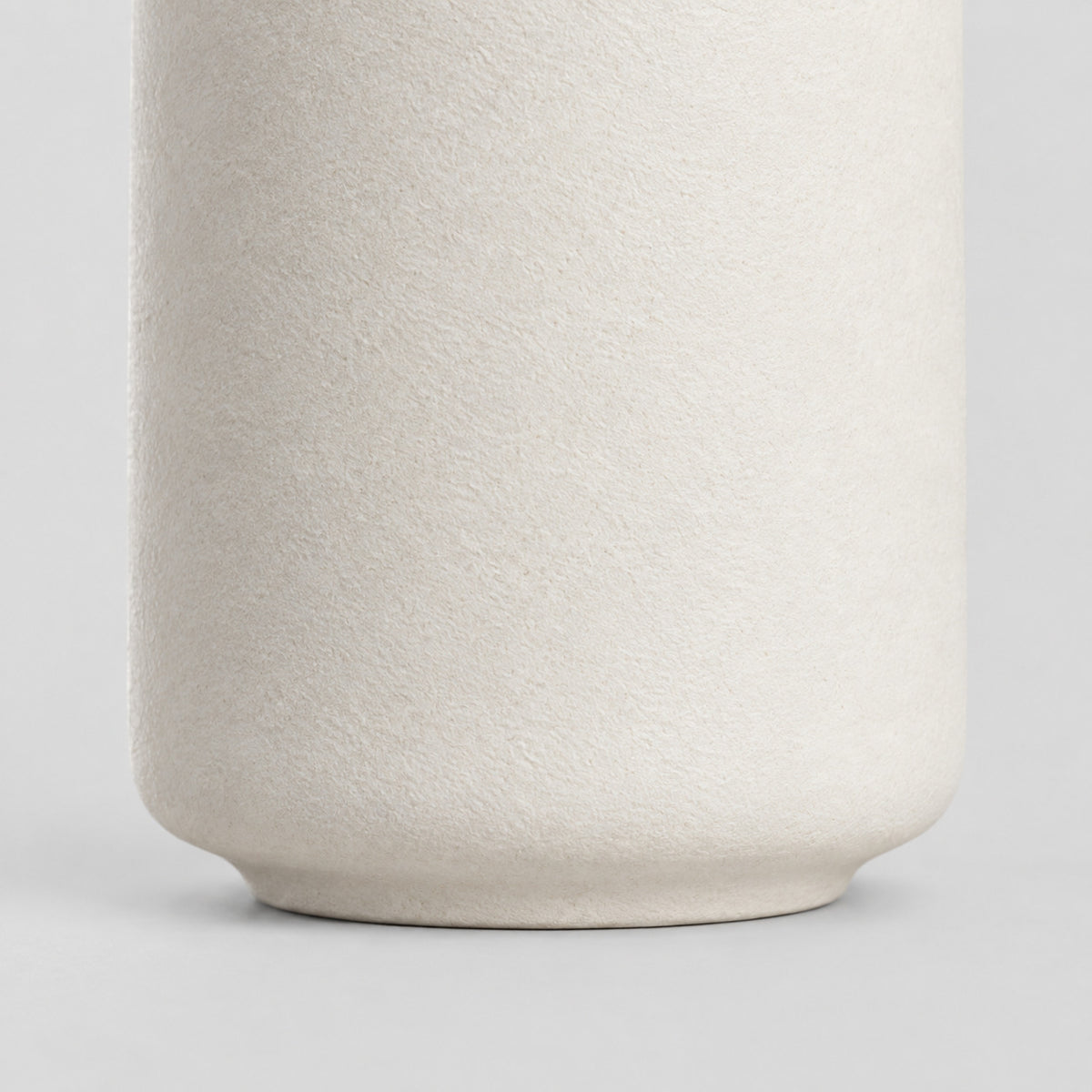 Close up of the smooth unglazed foot at the base of the Off-White matte ceramic bud vase.