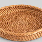 Close up of the tight spiral weave across the base of the shallow round woven rattan basket tray in Natural Rattan.