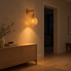 Natural wood woven bamboo wall sconce lit in the evening beside a doorway, the only light in the room