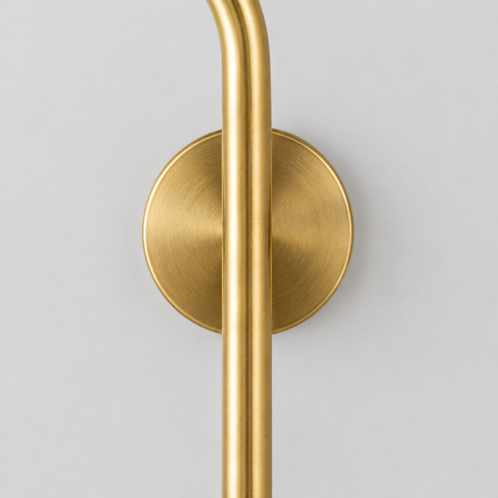 Close up of the round canopy against the wall of the brass wall sconce.