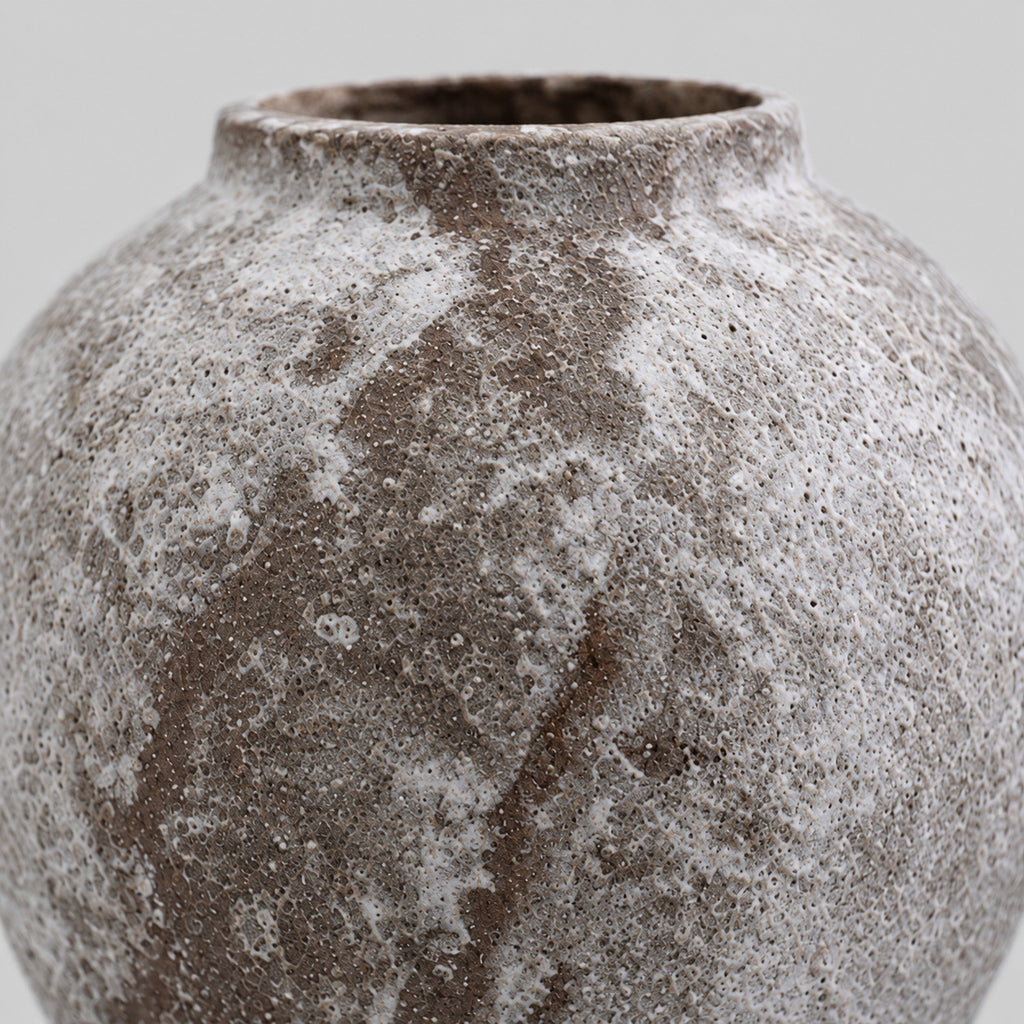 Close up of the textured mottled glaze on the rounded body of the weathered ceramic vase in Weathered Brown.