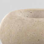 Close up of the curved smooth upper rim of the travertine candle holder.