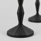 Close up of the textured round base of the set of two faceted cast iron taper candle holders