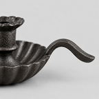 Close up of the curved cast iron handle of the cast iron chamberstick candle holder