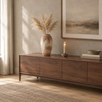 Textured ceramic vase on a walnut sideboard with dried pampas stems in the vase.