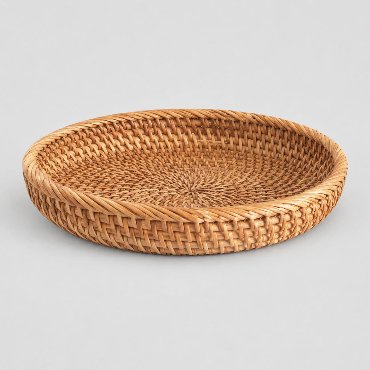 Shallow round woven rattan basket tray in Natural Rattan on a light gray studio background.