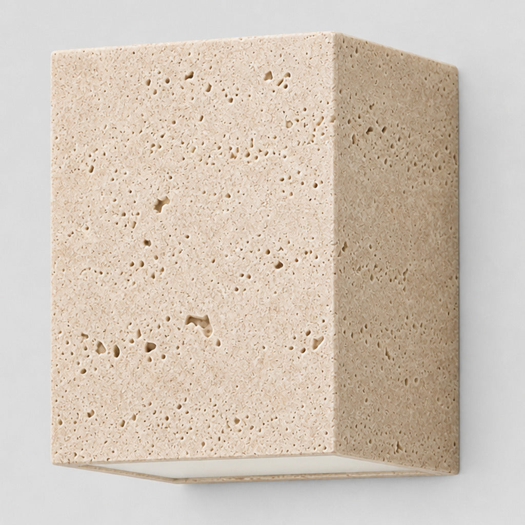Travertine block wall sconce in travertine on a light gray studio background, in its Cube shape