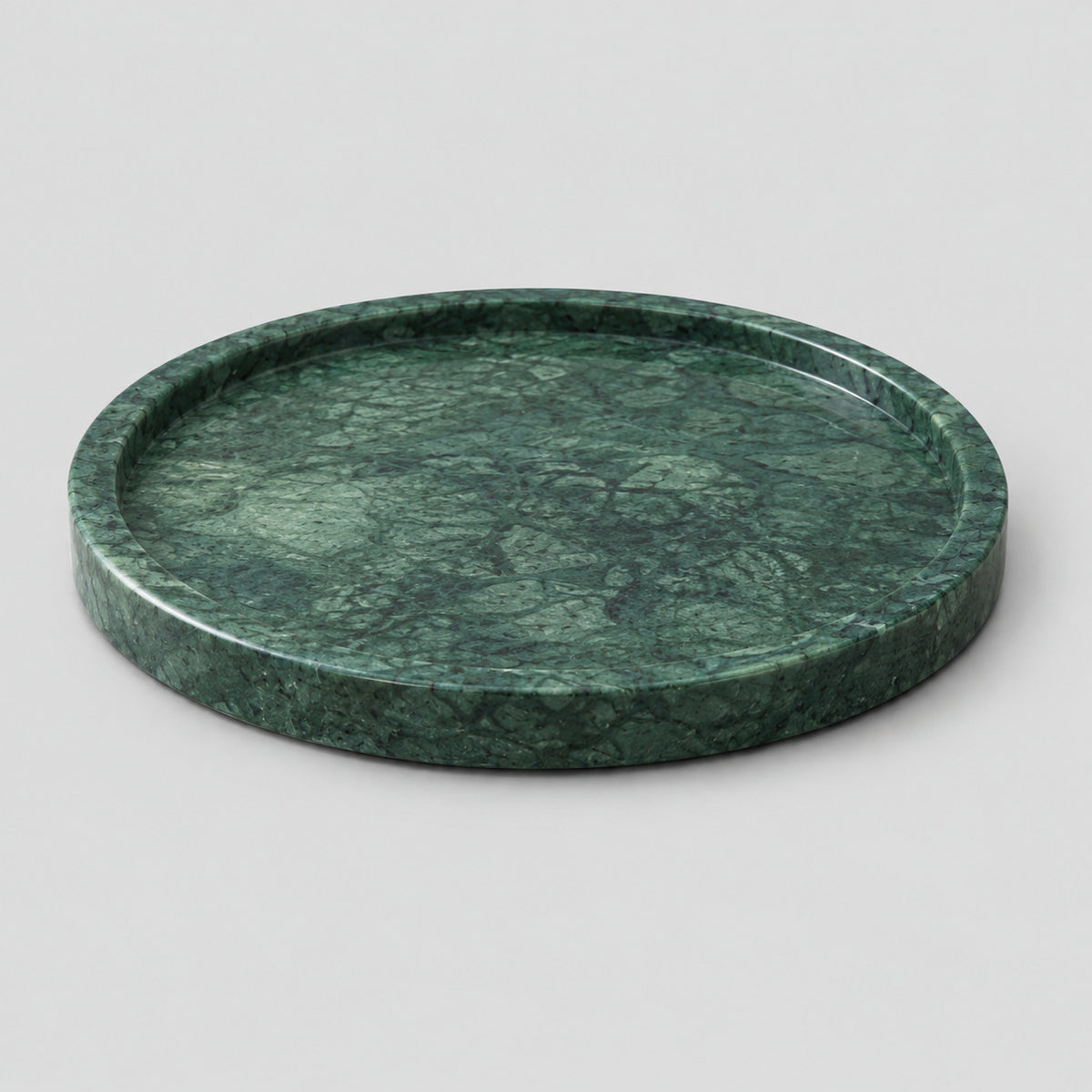 Round marble tray in Emerald Green Marble on a light gray studio background.